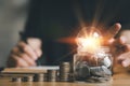 businessman holding lightbulb with using calculator to calculate and money stack. idea saving energy and accounting finance Royalty Free Stock Photo