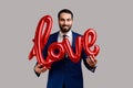 Businessman holding love word of foil balloons, expressing positive emotions and his feelings. Royalty Free Stock Photo