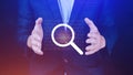 Businessman holding magnifying glass icon hologram in hand. Technology business and job search concept Royalty Free Stock Photo