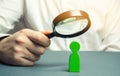 A businessman is holding a magnifying glass over a green man figure. Search for a talented employee. Identifying strengths in the Royalty Free Stock Photo