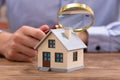 Businessman Holding Magnifying Glass Over House Model Royalty Free Stock Photo