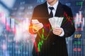 Businessman Holding money US dollar bills on digital stock market financial exchange information and Trading graph background