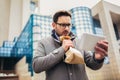 Businessman holding paper bag over mouth as if having a panic attack and looking in digital tablet Royalty Free Stock Photo