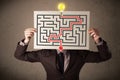 Businessman holding a paper with a labyrinth on it in front of his head