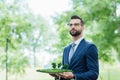 Businessman holding park layout with sun batteries and looking away while standing in park