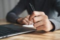 Businessman holding pen by left hand working with laptop at office Royalty Free Stock Photo