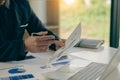 Businessman holding pen and paper pointing chart summary analysis calculating annual business report using laptop at desk in offic Royalty Free Stock Photo