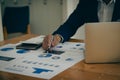 Businessman holding pen and paper pointing chart summary analysis calculating annual business report using laptop at desk in offic Royalty Free Stock Photo