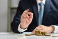 Businessman holding a pen and pointing something with stack of gold coin. Investment and financial management concept Royalty Free Stock Photo