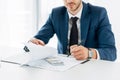 Businessman holding pen while signing contract near money on table Royalty Free Stock Photo