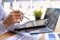 A businessman holding a pen and tablet to check financial information from files sent by the finance department via email, he is a Royalty Free Stock Photo