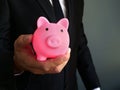 Businessman holding piggy bank as symbol of savings