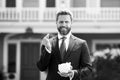 Businessman holding piggy bank on home house background. Handsome caucasian man holding piggybank for money for savings. Royalty Free Stock Photo