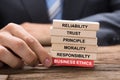 Businessman Holding Red Business Ethics Block Under Wooden Tower