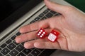 Businessman holding red dices while using laptop