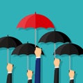 BusinessMan holding a red umbrella among people with black umbrellas. Standing out from the crowd. Difference concept