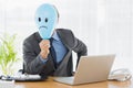 Businessman holding sad smiley faced balloon at office Royalty Free Stock Photo