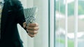 Businessman holding several $100 bills in his hand, payroll concept.