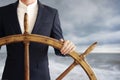 Businessman holding ship rudder and navigates in storm Royalty Free Stock Photo