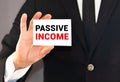 Businessman holding or showing card with text passive income