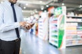 Businessman holding the smart phone on Supermarket blur background