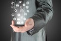 Businessman holding smart phone from which flying social media apps icons, on grey background, social media in smart phone concept