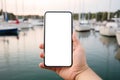 Businessman holding smartphone with blurred yacht marine background. White screen, mockup
