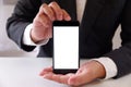 Businessman holding smartphone forward empty white screen for your text or picture.