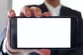 Businessman holding smartphone forward empty white screen for your text or picture.