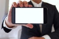 Businessman holding smartphone forward empty white screen for your text or picture Royalty Free Stock Photo