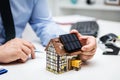 Businessman holding a solar panel on a symbolic farmhouse, green energy