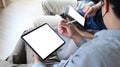 Businessman holding stylus pen and using digital tablet with his friend on sofa. Royalty Free Stock Photo