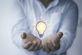 Businessman holding virtual lightbulb glowing on hand for creative thinking idea and innovative technology concept