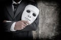 Businessman holding white mask in his hand dishonest cheating agreement.Faking and betray business partnership concept