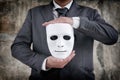 Businessman holding white mask in his hand dishonest cheating agreement.Faking and betray business partnership concept