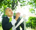 Businessman holding wind turbine in the woods
