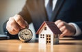 Businessman holding a wooden house and clock. Mortgage, real estate and loan concept. Tax payment. Construction investment.