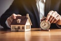 Businessman holding a wooden house and clock. Mortgage, real estate and loan concept. Tax payment. Construction investment. Royalty Free Stock Photo