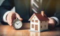 Businessman holding a wooden house and clock. Mortgage, real estate and loan concept. Tax payment. Construction investment. Royalty Free Stock Photo