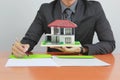 Businessman holding wooden house and signing documents on the table, New home and real estate concept Royalty Free Stock Photo