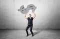 Businessman holds a big heavy concrete dollar object with sleeves rolled up.