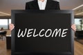 Businessman holds a big signboard with the message welcome Royalty Free Stock Photo