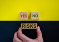 Businessman holds a block with word `risks`. Wooden cubes with words `yes, no`. Beautiful yellow and black background. Copy s