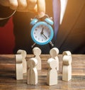 A businessman holds a blue clock over a team of workers. Time management concept. Deadline. Teamwork. Scrum. Human resources.