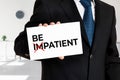 Businessman holds a card with the word be impatient transformed into be patient