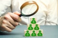 Businessman holds magnifying glass over cubes with dollars. Analysis of profits and revenues in the company. Distribution of money