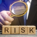 Businessman holds a magnifying glass over the word Risk. Financial and commercial risk concept. Risks assessment and management. Royalty Free Stock Photo