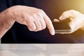 Businessman holds a mobile phone in his hand and his finger points towards a wooden office desk with copy space Royalty Free Stock Photo