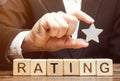 Businessman holds one star above the wooden blocks with the word Rating. Concept of negative feedback. Low quality and service