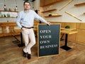 Businessman holds Open your own business sign